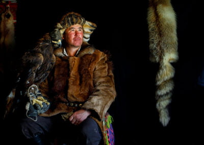B. Baibolat, a Kazak eagle hunter, sitting inside his ger with his eagle.