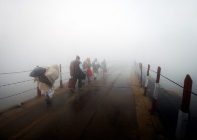 Devotees are crossing the pontoon bridge in dense fog