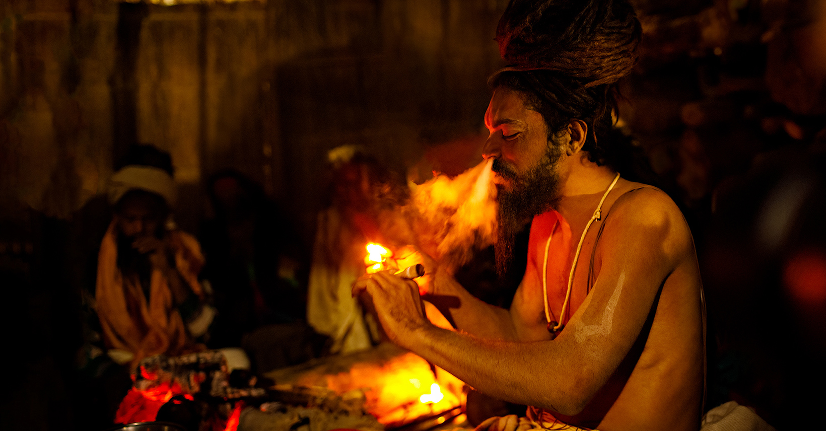 A Naga Sadhu smokes a chillum at the Kumbh Mela in Allahabad, India. I am fortunate enough to be connected with so many Naga Babas. I have made this image during Allahabad Kumbh Mela 2019. Naga Sadhus are found all over the country but they are exclusively from the Himalayas. Deep in the mountains of the Himalayas, these sadhus live in subzero temperatures, wearing nothing more than a single piece of cloth and taking very minimum food. As they are in the search of enlightenment, they have very strict rules to be followed as they need to conserve energy for their concentration and meditation. They consume a certain amount of ‘charas’ or ‘hash’, which exclusively grows only in the Himalayan mountains. This specific kind of ‘charas’, when consumed produces an immense amount of heat in the body, so it helps them to cope up with the extreme cold temperatures in the mountains. Kumbh Mela, the largest spiritual gathering of mankind on the Earth, is held every 12 years on the banks of the 'Sangam'- the confluence of the holy rivers Ganga, Yamuna and the mythical Saraswati. Millions of devotees take a holy dip in the sacred water during the mela. Maha Kumbha Mela held only at Prayag, once in every 144 years. It is believed that at the historic moment of the Maha Kumbh Mela, the river turns itself into sanctity spots filled with ‘Amrita’ (Panacia or elixir of immortality). The pilgrims get once in a lifetime chance to bathe in the spirit of holiness, auspiciousness and salvation.