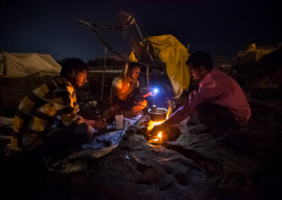 Three camel shepherds are preparing their food at night during Pushkar Mela.